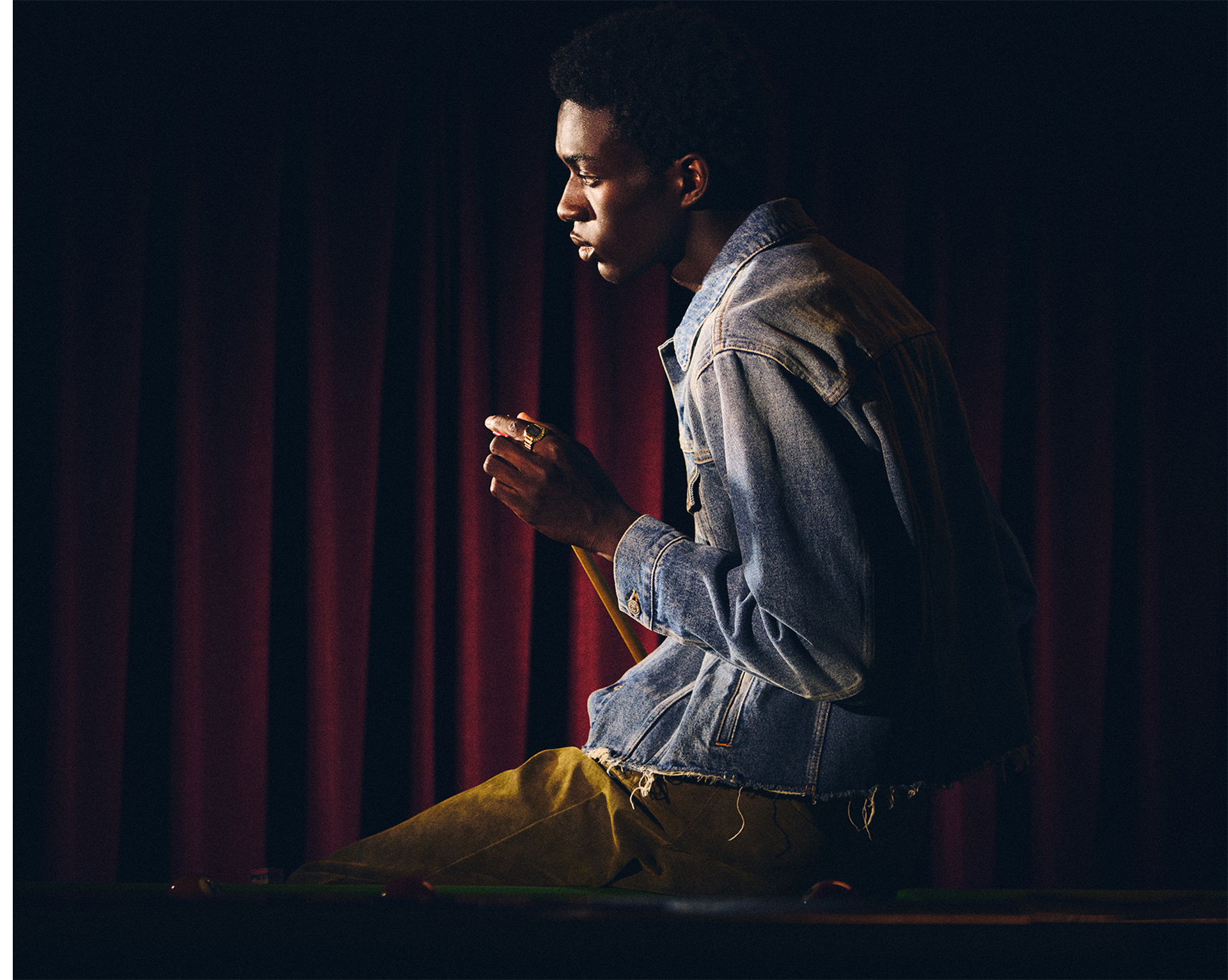 一名手指上戴着 CRW-001G 的男子坐在台球桌前触摸球杆的照片。