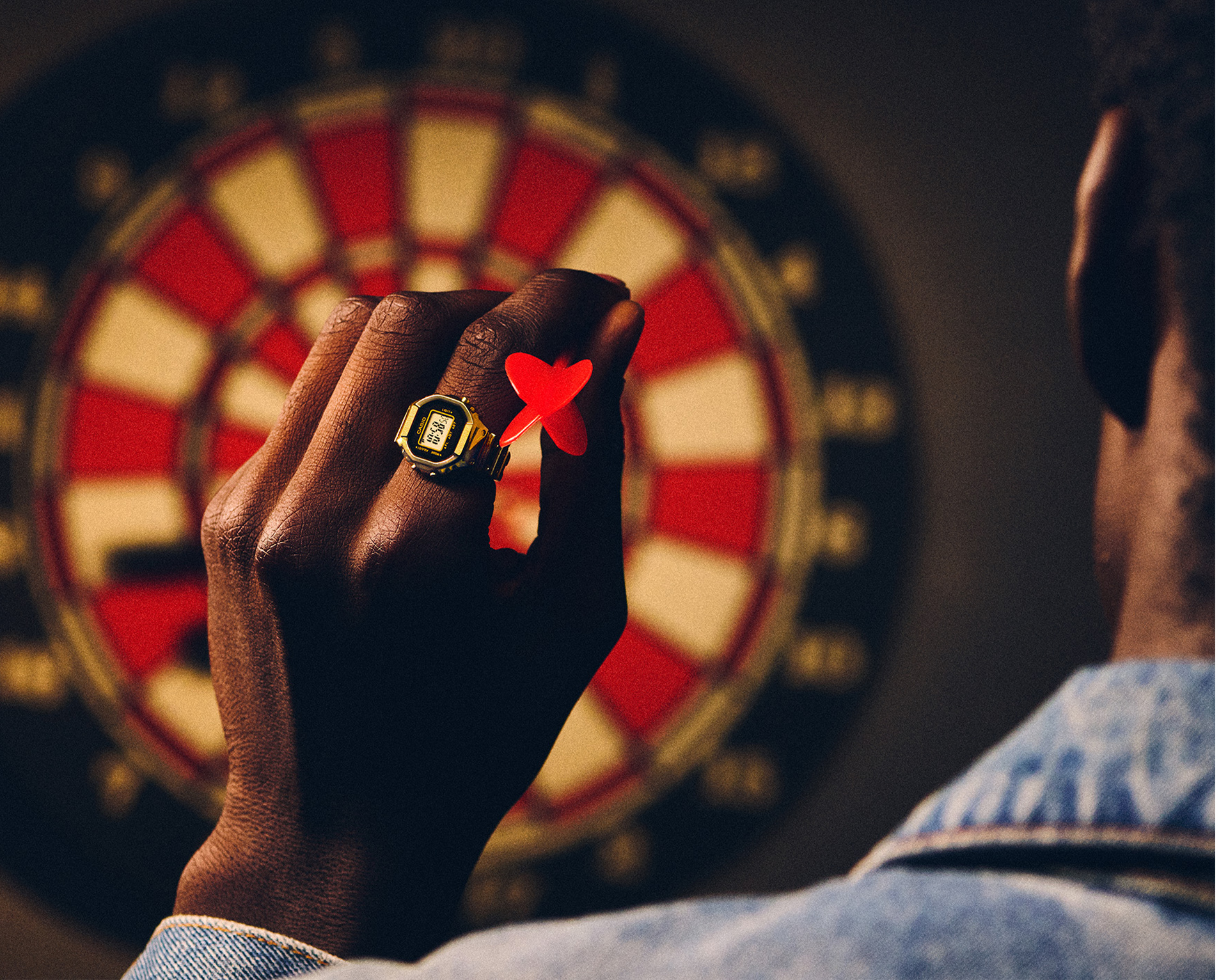 一名男子手指上戴着 CRW-001G 并在玩飞镖的照片。