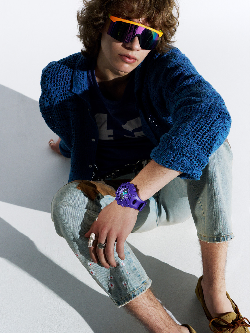 佩戴紫色 G-SHOCK 和太阳镜，随意坐着的人。