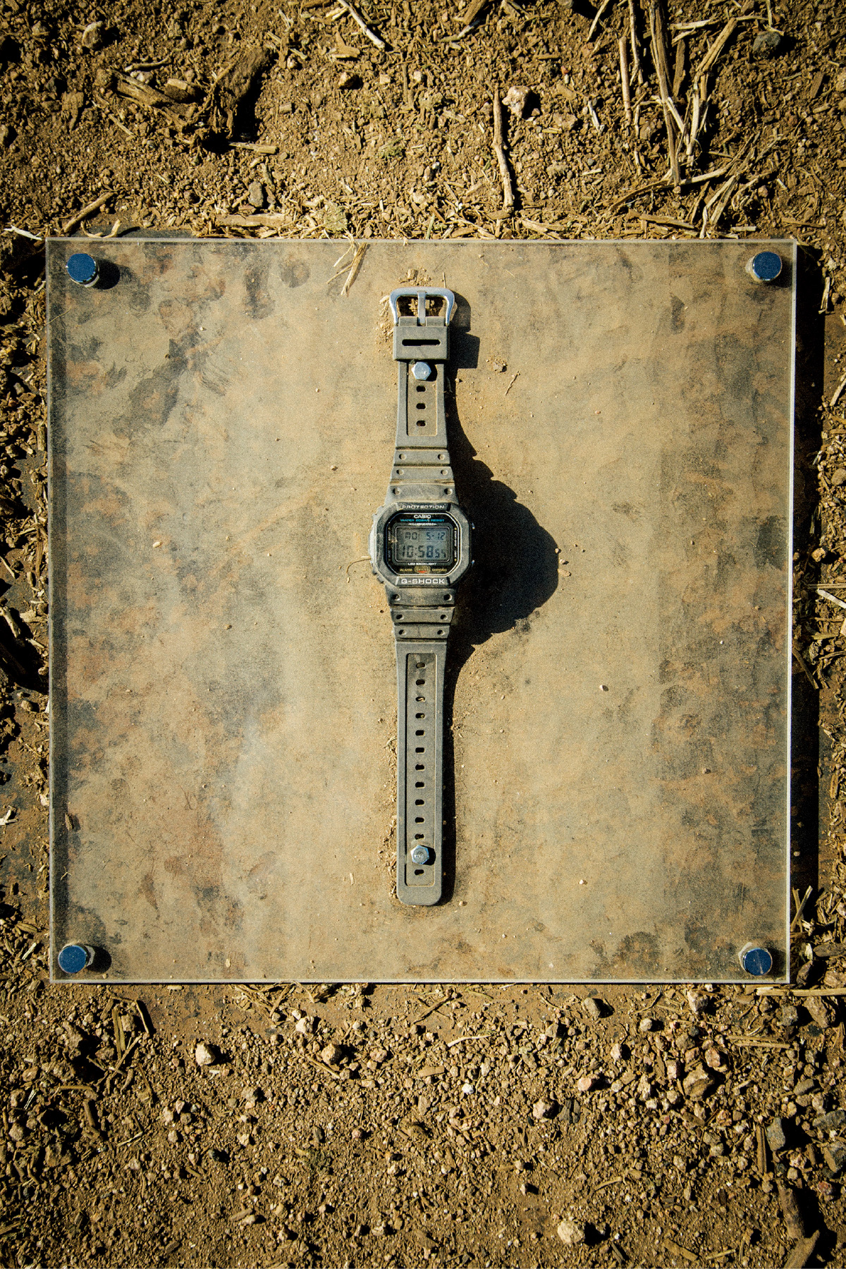 一张黑色 G-SHOCK 被一辆半挂卡车碾压后满身尘土的照片。